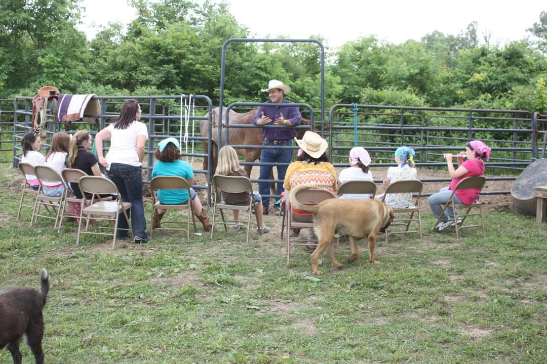A ranch leader teaching a group of young people beside the horses